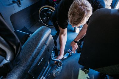 Chauffeurs de TSMO sécurisant un fauteuil roulant à l'intérieur du véhicule